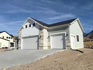 View of side of home with driveway, an attached garage, and stone siding