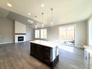 Kitchen with pendant lighting, open floor plan, recessed lighting, vaulted ceiling, and a large fireplace