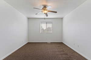 Unfurnished room with dark colored carpet, a textured ceiling, and a ceiling fan