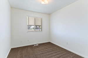 Unfurnished room featuring dark colored carpet and baseboards
