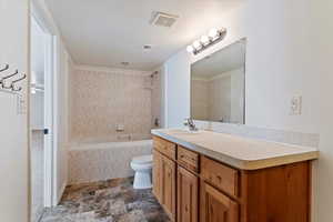 Bathroom featuring tiled shower / bath, vanity, and stone finish floors