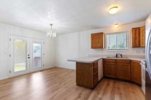 Kitchen featuring a peninsula, light countertops, brown cabinetry, light wood-style floors, and a textured ceiling
