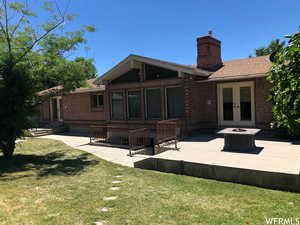 Back of house with a patio area, brick siding, a lawn, french doors, and a chimney