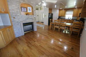 Kitchen featuring freestanding refrigerator, light wood finished floors, a fireplace, ceiling fan, and open shelves