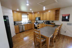 Kitchen with stainless steel appliances, light wood-type flooring, open shelves, and recessed lighting