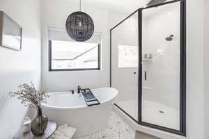 Bathroom with a stall shower, a freestanding bath, and light tile patterned floors