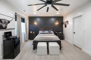 Bedroom with light carpet, a ceiling fan, a decorative wall, and recessed lighting
