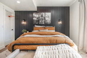 Bedroom featuring wooden walls, a textured ceiling, and wood finished floors
