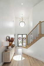 Entryway with light wood-style floors, stairs, a chandelier, a towering ceiling, and recessed lighting