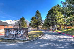 Community sign featuring a mountain view and a lawn