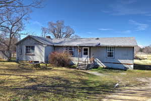 View of front of home featuring a front yard, a chimney, and roof with shingles