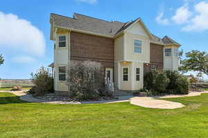 Back of property with a lawn, brick siding, and a shingled roof