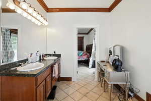 Ensuite bathroom with ornamental molding, double vanity, and light tile patterned floors