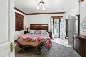 Master en-suite Bedroom with light tile patterned flooring, light colored carpet, and crown molding