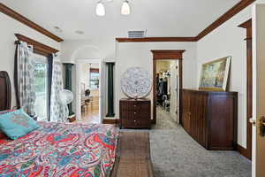 Carpeted bedroom featuring a spacious closet, ornamental molding, and access to outside