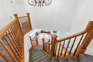Staircase with a high ceiling, a chandelier, and wood finished floors