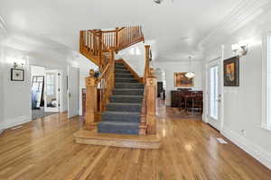 Entrance foyer featuring ornamental molding, arched walkways, wood finished floors, and healthy amount of natural light