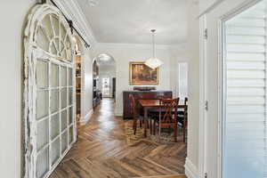 Dining area with arched walkways, ornamental molding, and a chandelier