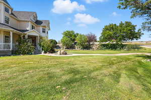 View of grassy yard featuring covered porch