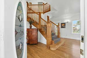 Stairs featuring wood finished floors and crown molding