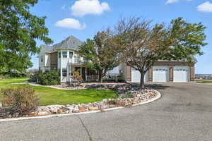 View of front of house featuring a front lawn, a garage, asphalt driveway, and a balcony