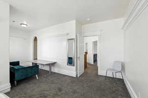 Unfurnished room featuring dark carpet and arched walkways