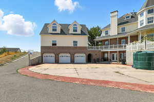 View of side of property with driveway, brick siding, a garage, and a balcony