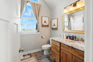 Half bathroom featuring vanity, light wood-style flooring, and lofted ceiling