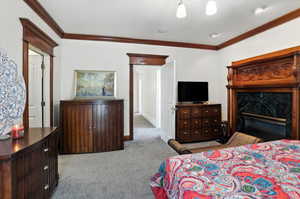 Bedroom featuring crown molding, light carpet, and a high end fireplace