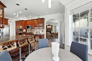 Kitchen with arched walkways, dark granite counters, decorative backsplash, decorative light fixtures, and stainless steel appliances