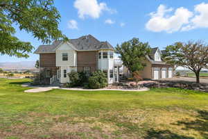 View of front facade featuring a front yard, a garage, brick siding, driveway, and a mountain view