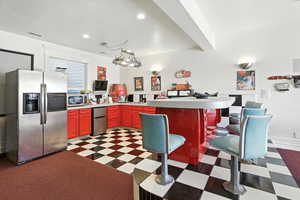 Kitchen with stainless steel appliances, light countertops, recessed lighting, dark flooring, and a peninsula