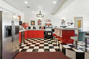 Kitchen with stainless steel refrigerator with ice dispenser, recessed lighting, light countertops, dark flooring, and stainless steel fridge