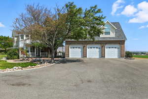 View of front facade with covered porch, a garage, brick siding, asphalt driveway, and roof with shingles