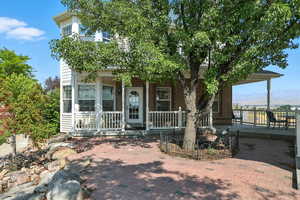 View of property hidden behind natural elements featuring a porch and brick siding