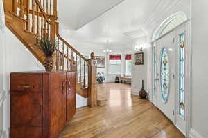 Entrance foyer with light wood-type flooring, stairs, and a chandelier