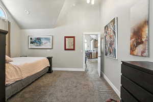 Bedroom featuring carpet flooring, high vaulted ceiling, and ensuite bath