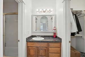 Bathroom featuring a stall shower and granite vanity