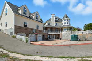 Rear view of property featuring brick siding, a balcony, concrete driveway, and an attached garage