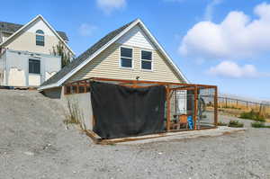 View of side of property with an exterior structure, an outbuilding, and a shingled roof
