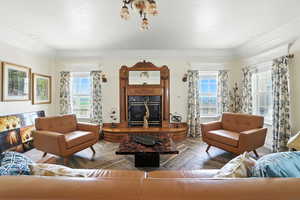 Living room featuring a high end custom fireplace, healthy amount of natural light, and crown molding