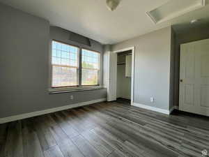 Unfurnished bedroom featuring attic access, dark wood-type flooring, and a closet