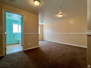 Unfurnished room featuring dark carpet and a textured ceiling