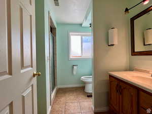 Full bath featuring vanity, a shower stall, a textured ceiling, and light tile patterned floors