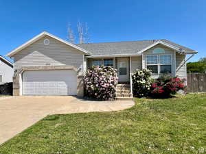 Ranch-style home featuring roof with shingles, driveway, a garage, and a porch