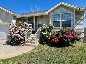 Doorway to property featuring a yard, a porch, roof with shingles, and a garage