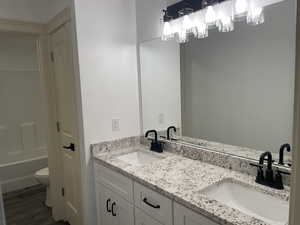 Full bathroom with double vanity and dark wood-style floors