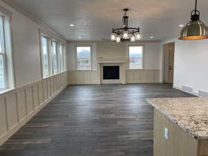 Unfurnished living room with ornamental molding, dark wood finished floors, a fireplace, a decorative wall, and recessed lighting