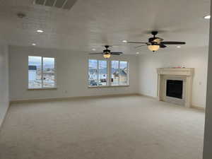 Unfurnished living room with light carpet, a fireplace, recessed lighting, and a textured ceiling
