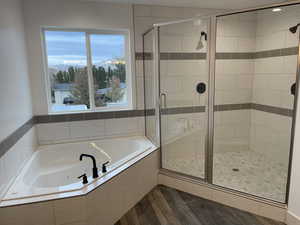 Bathroom featuring a stall shower, a garden tub, and dark wood finished floors